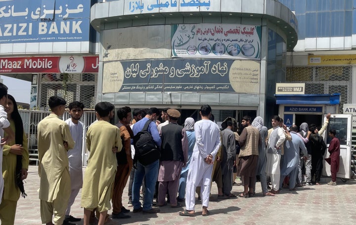 Afghan people line up outside AZIZI Bank to take out cash as the bank suffers amid money crises in Kabul, Afghanistan, on Sunday. 