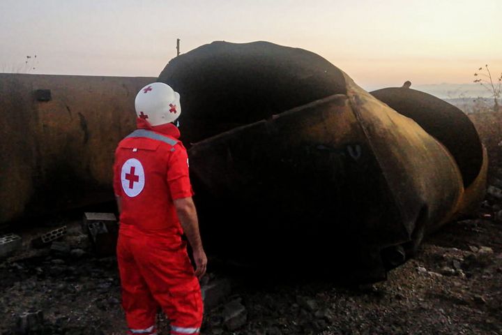 15 August 2021, Lebanon, Talil: A red cross volunteer stands near fuel tanks that exploded last night in the Lebanese northern village of Talil. At least 28 people died and 79 others were injured while the army was handing out gasoline to residents after had seized a fuel storage tank hidden by black marketers. (Best quality available) Photo: Stringer/dpa (Photo by Stringer/picture alliance via Getty Images)