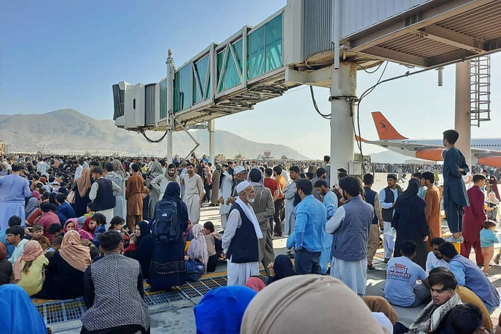 Afghans crowd at the tarmac of the Kabul airport to flee the country. 