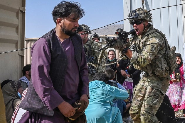A US soldier point his gun towards an Afghan passenger at the Kabul
