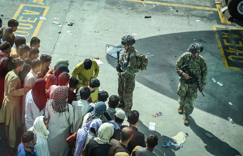 US soldiers stand guard as Afghan people wait at the Kabul airport in Kabul on August 16,