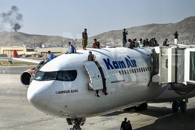 Des Afghans sur le toit d'un avion à l'aéroport de Kaboul le 16 août 2021