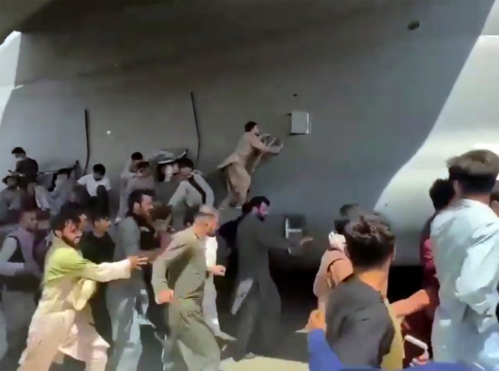 Hundreds of people run alongside a U.S. Air Force C-17 transport plane, some climbing on the plane, as it moves down a runway of the international airport, in Kabul, Afghanistan, Monday, Aug.16. 2021. (Verified UGC via AP)