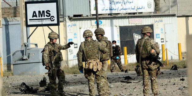 U.S. soldiers speak at the site of a suicide attack in Kabul, Afghanistan, Monday, Oct. 13, 2014. An Afghan official said a suicide bomber targeting a NATO convoy in Kabul has killed one civilian and wounded three others. (AP Photo/Massoud Hossaini)