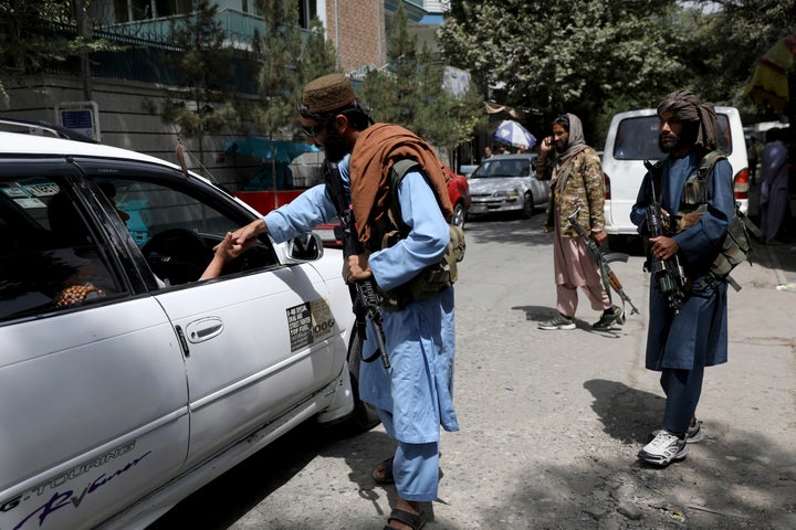 Taliban fighters stand guard at a checkpoint in Wazir Akbar Khan.