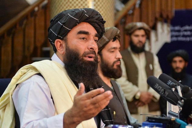Taliban spokesperson Zabihullah Mujahid (L) gestures as he speaks during the first press conference in...