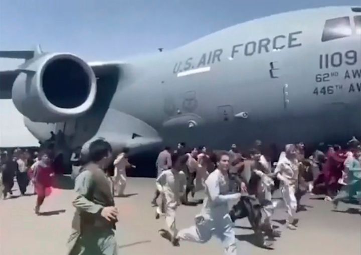 Some hundreds of people run alongside a U.S. Air Force C-17 transport plane as it moves down a runway of the international ai