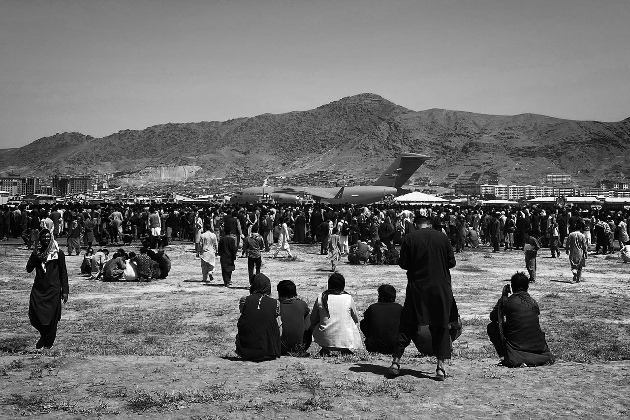 Hundreds of people gather near a U.S. Air Force C-17 transport plane at the perimeter of the international airport in Kabul on Monday.