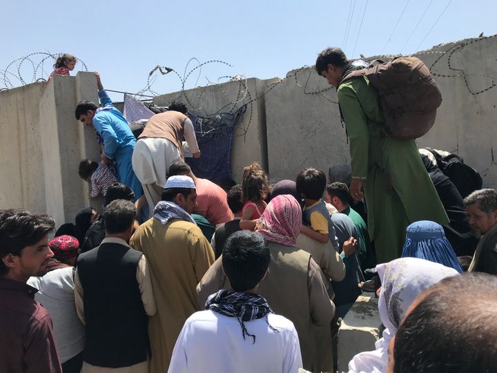 People struggle to cross the boundary wall of Kabul's Hamid Karzai International Airport on Monday to flee the country.