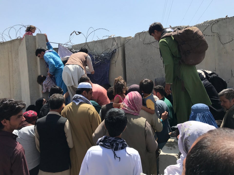 People struggle to cross the boundary wall of Kabul's Hamid Karzai International Airport on Monday to...