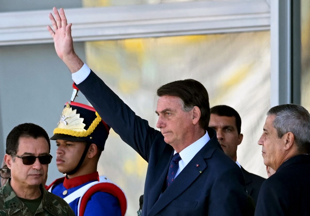 Flanked by a former general and the commander of the navy, far-right Brazil President Jair Bolsonaro watches a military parade from the steps of the presidential palace on Aug. 10.