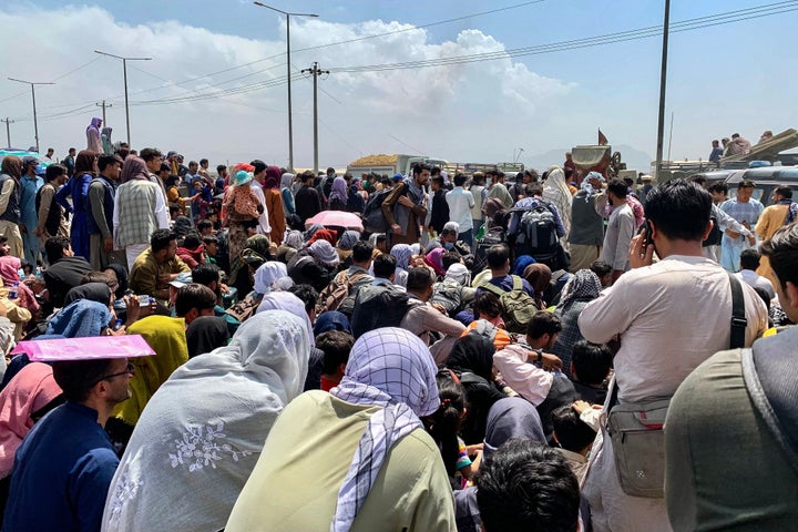 Afghan people gather along a road as they wait to board a U.S. military aircraft to leave the country, at a military airport in Kabul on Aug. 20, days after Taliban's military takeover of Afghanistan.