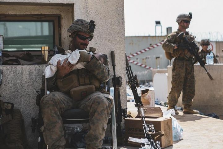 A Marine assigned to the 24th Marine Expeditionary Unit calms an infant during an evacuation at Hamid Karzai International Ai