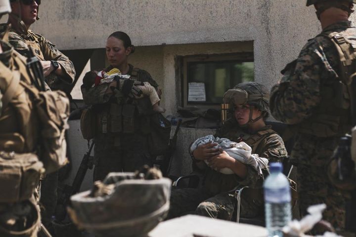 Marines assigned to the 24th Marine Expeditionary Unit calm infants during an evacuation at Hamid Karzai International Airport, Kabul, Afghanistan, Aug. 20.