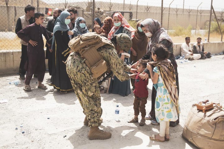 A U.S. Navy Sailor checks a child arriving at an Evacuate Control Center at Hamid Karzai International Airport, Aug. 19.