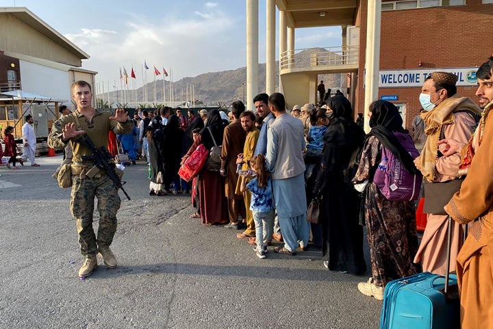 Afghan people line up to board a U.S. military aircraft to leave Afghanistan at the military airport in Kabul on Aug. 19 after Taliban's military takeover of Afghanistan.