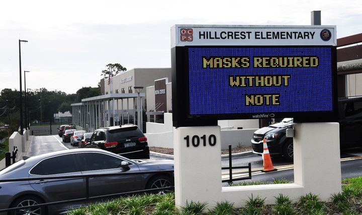 On Aug. 16, parents drop their kids off at Hillcrest Elementary school in Orlando with a sign at the entrance advising for the requirement of face masks for students unless the parents opt out of the mandate by writing a note to school officials.