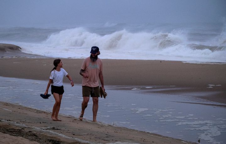 Ryan Madigan, and his daughter Charolette Madigan, 11, of Cold Spring Harbor, N.Y., stand along a beach in Montauk, N.Y., Saturday, Aug. 21, 2021, as Henri churns up waves as the storm approaches. (AP Photo/Craig Ruttle)