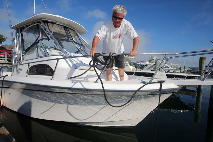 Rob Edwards, from Newport, R.I., adds extra lines to secure his boat at the Goat Island Marina, Saturday, Aug. 21, 2021, in Newport, R.I. (AP Photo/Stew Milne)