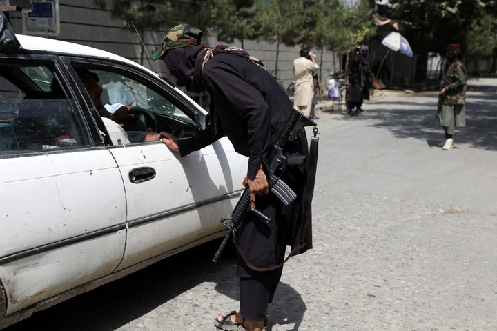 Taliban fighters search a vehicle at a checkpoint on a road in the Wazir Akbar Khan neighborhood on Sunday. 