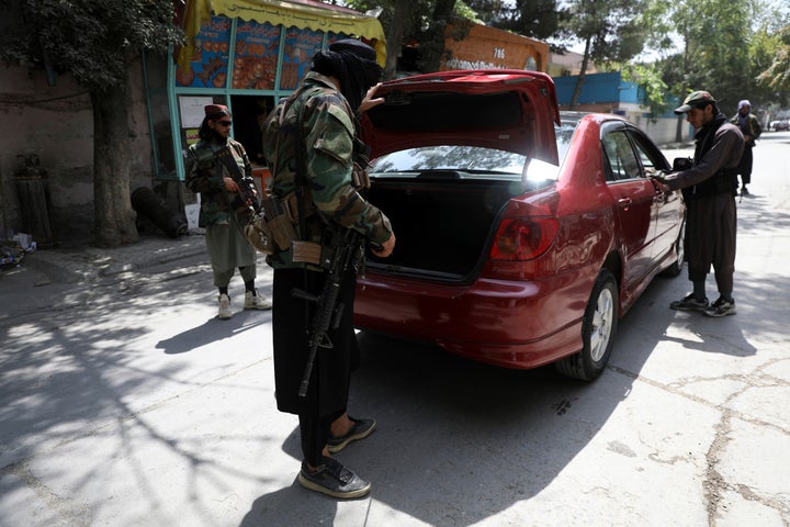 Taliban fighters search a vehicle at a checkpoint on a road in the Wazir Akbar Khan neighborhood on Sunday.