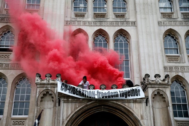 Protesters from Extinction Rebellion light a flare and unfurl a banner from the Guildhall on August 22,...