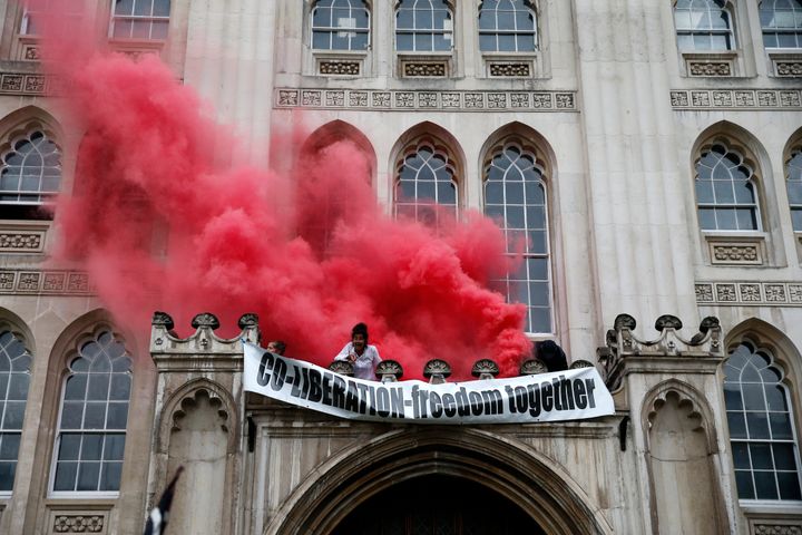 Protesters from Extinction Rebellion light a flare and unfurl a banner from the Guildhall on August 22, 2021 in London, England