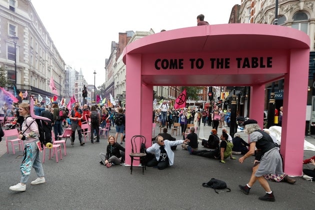 People participate in a protest of Extinction Rebellion climate activists next to a big model table,...