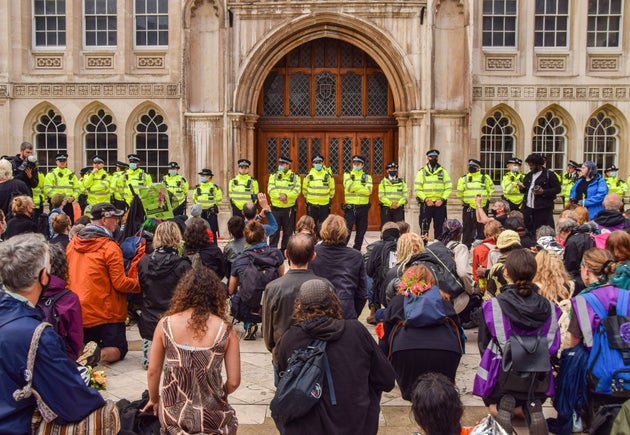 Protesters kneel down while police officers guard the Guildhall building entrance during the