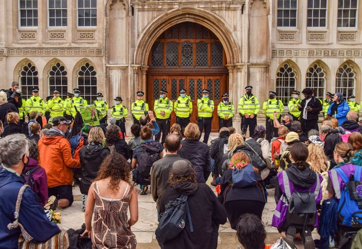 Protesters kneel down while police officers guard the Guildhall building entrance during the demonstration