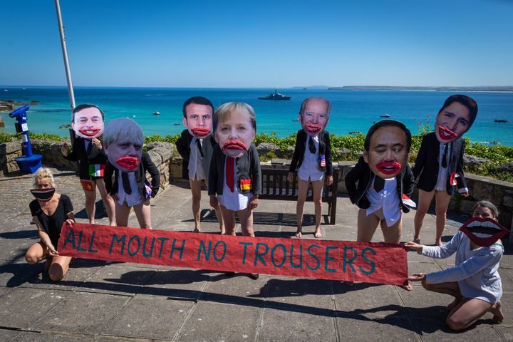 Extinction Rebellion protesters wearing cartoon heads of the G7 leaders pose with a banner reading "All Mouth No Trousers" in Cornwall, June 2021
