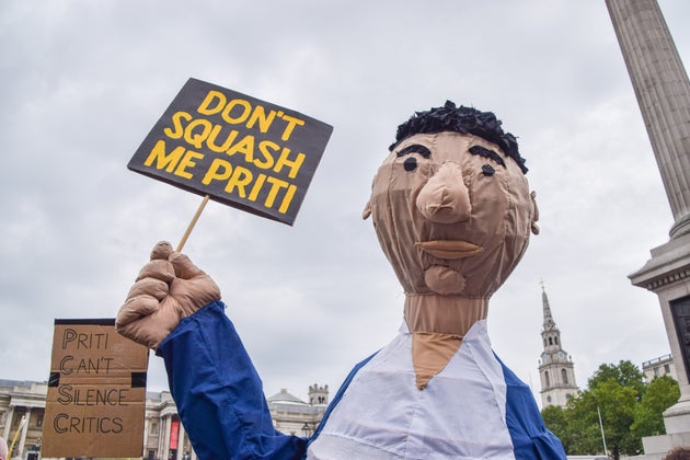 A demonstrator wearing a costume holds a placard which says 'Don't Squash Me Priti (Patel)' during the...