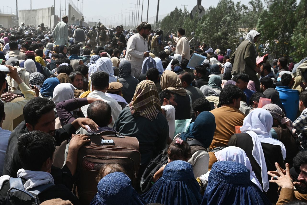 Afghans gather on a roadside near the military part of the airport in Kabul on August 20, 2021