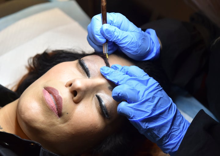 A woman gets her brows microbladed.