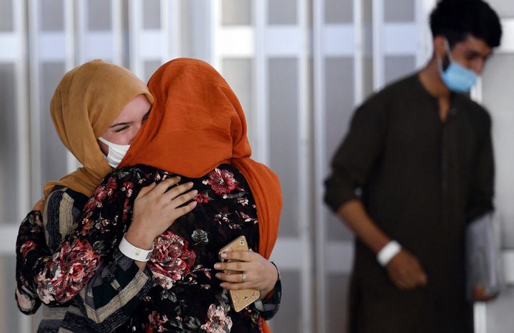 A woman embraces her sister-in-law (L) as she arrives with other Afghan refugees at Dulles International Airport on Aug. 23.