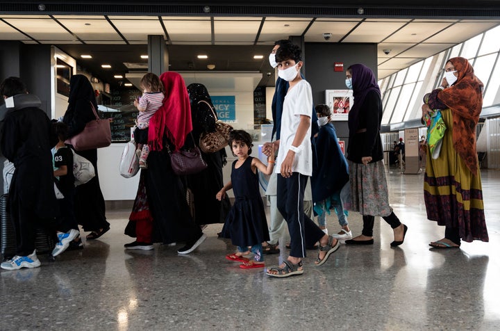 Afghan refugees are escorted to a waiting bus after arriving and being processed at Dulles International Airport on Aug. 23.