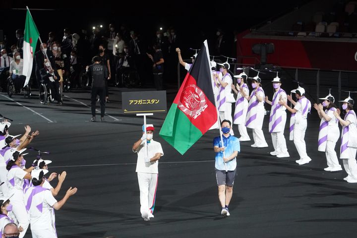 東京パラリンピックの開会式でアフガニスタン国旗を掲げて行進する大会ボランティア