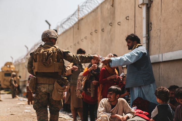 A Marine with the 24th Marine Expeditionary unit (MEU) passes out water to evacuees during the evacuation at Hamid Karzai International Airport during the evacuation on August 21, 2021
