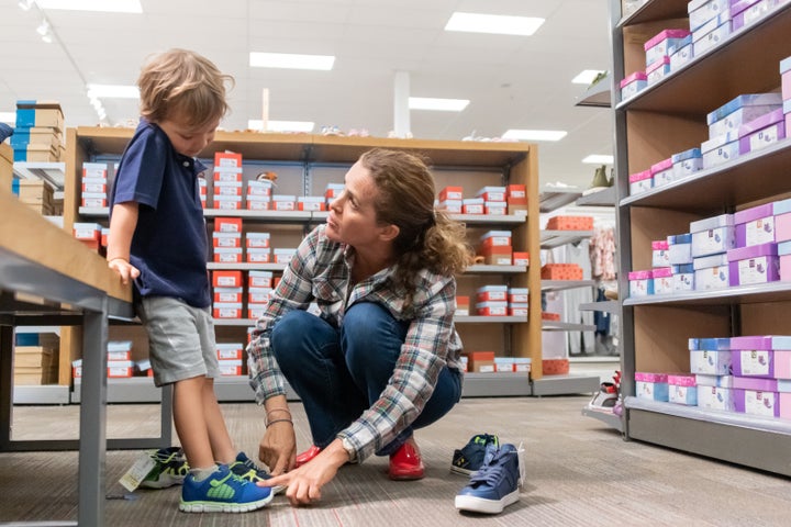 Una mujer comprando zapatos para su hijo en una tienda.