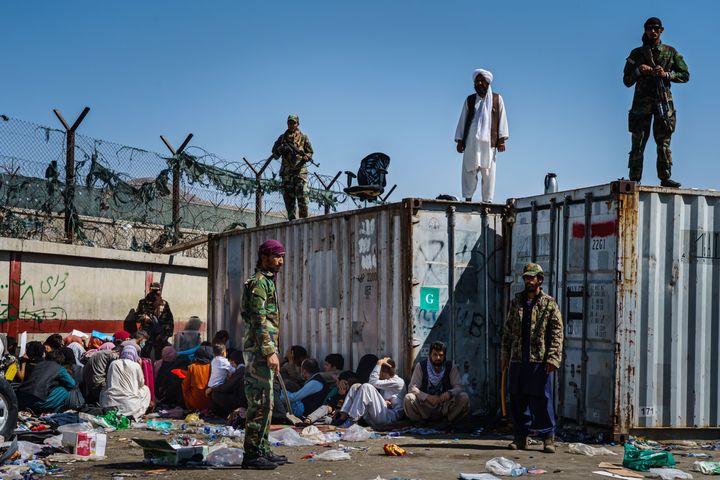 Μαχητές των Ταλιμπάν περιφρορούν πύλη στο αεοροδρόμιο της Καμπούλ ενώ Αφγανοί είναι σε αναμονή για να αναχωρήσουν από την χώρα τους , 25/8/2021. (MARCUS YAM / LOS ANGELES TIMES)