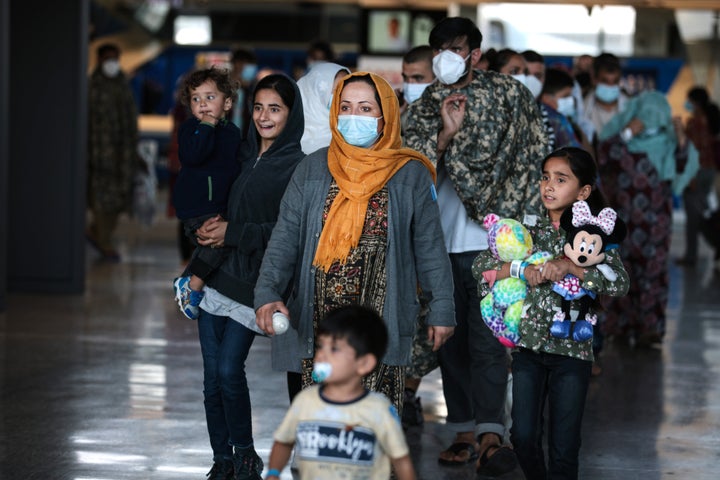 A family of people evacuated from Afghanistan are led through the arrival terminal at the Dulles International Airport to board a bus that will take them to a refugee processing center on Aug. 25, 2021 in Dulles, Virginia.