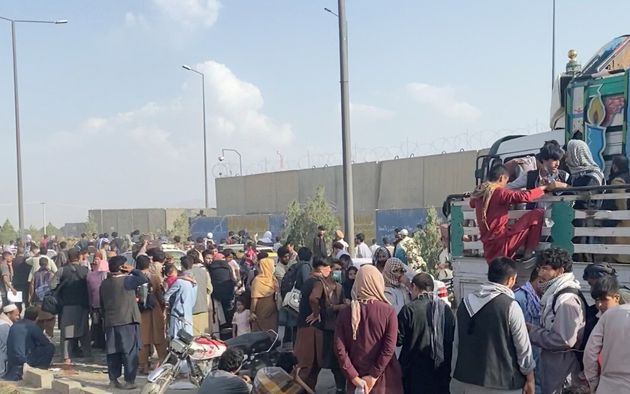 Des Afghans attendant devant l'aéroport de Kaboul, en Afghanistan, le 19 août 2021.