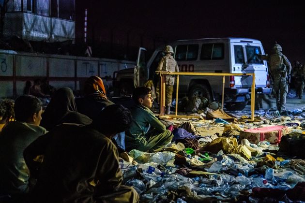 Des réfugiés afghans sont regroupés près de l'Abbey Gate de l'aéroport de Kaboul alors que des militaires britanniques sécurisent le périmètre à l'extérieur de l'hôtel Baron, en Afghanistan, le 26 août 2021. (MARCUS YAM / LOS ANGELES TIMES)