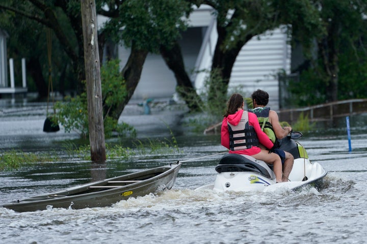 A local resident on a jet ski tows a canoe to a flooded house as outer bands of Hurricane Ida arrive on Sunday in Bay Saint Louis, Miss.