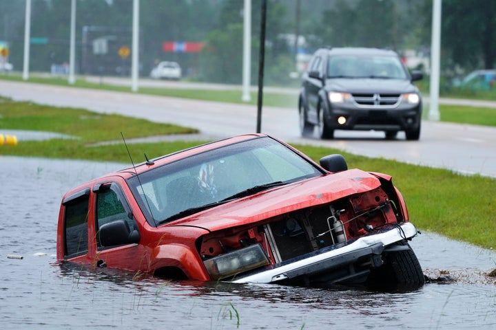 An abandoned vehicle is half submerged in a ditch next to a near flooded highway in Bay Saint Louis, Miss., on Sunday.