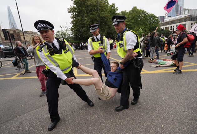 Police remove a man as members of Extinction Rebellion reach Tower Hill during their march in central