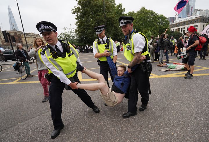 Police remove a man as members of Extinction Rebellion reach Tower Hill during their march in central London.