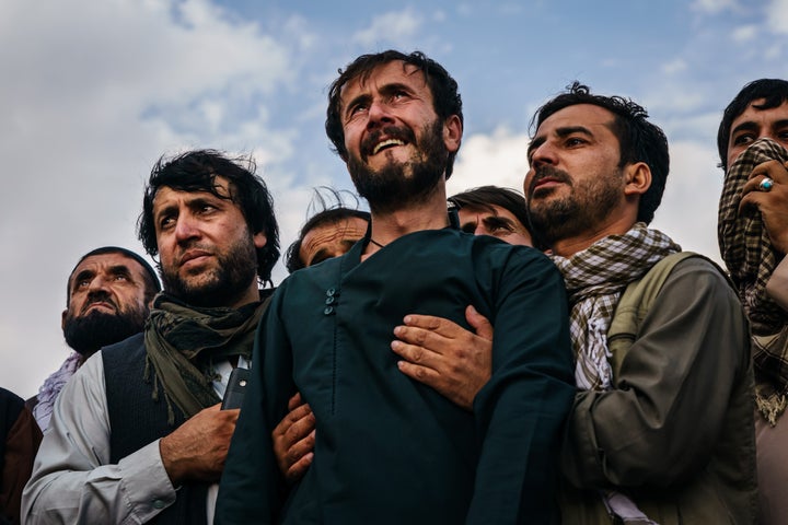 Ramal Ahmadi, center, is supported by family members as he weeps looking up at jet fighters circling above at the conclusion of the U.S. withdrawal. The family was attending a funeral Monday for the 10 people the family said were killed in a U.S. drone strike.