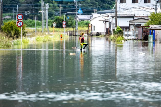 浸水した地域を歩く消防職員＝2021年8月15日、佐賀県武雄市