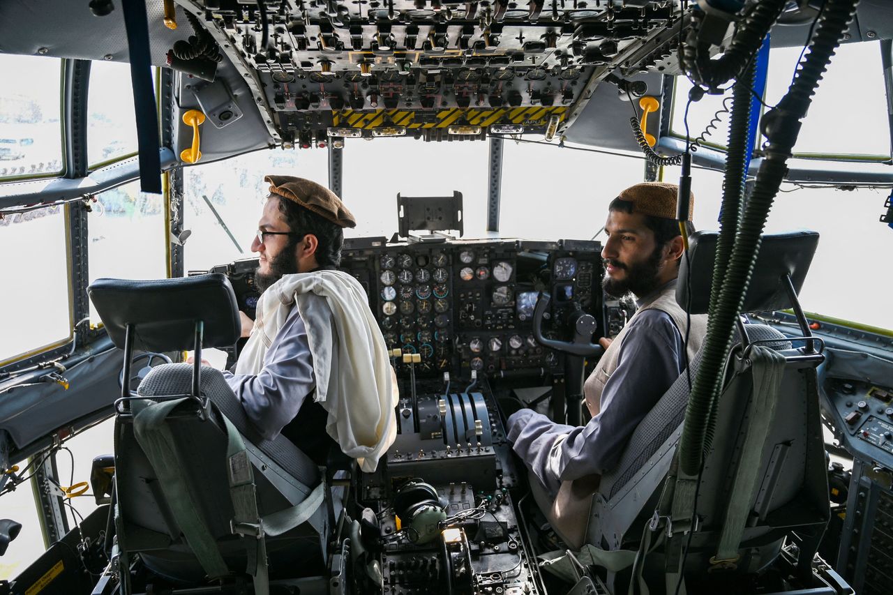 Taliban fighters sit in the cockpit of an Afghan Air Force aircraft at the airport in Kabul.